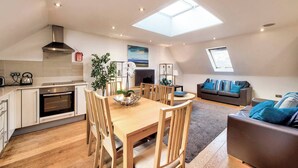 Ein modernes Apartment mit Küche, Essbereich und Wohnzimmer. Es verfügt über Dachfenster, einen Kamin und ein großes Fenster.