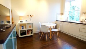 Una cocina moderna con armarios blancos, una mesa redonda de comedor con cuatro sillas y un ventanal con vistas a la ciudad.