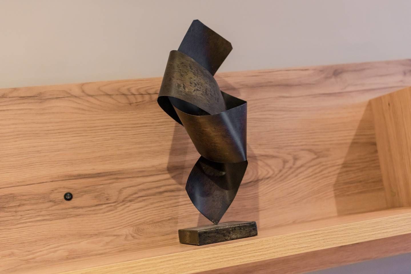 A metal sculpture on a wooden shelf.
