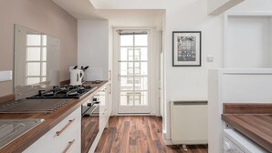 Une cuisine moderne équipée d’une cuisinière à gaz, d’un plan de travail en bois et offrant une vue sur l’extérieur grâce à une porte vitrée.