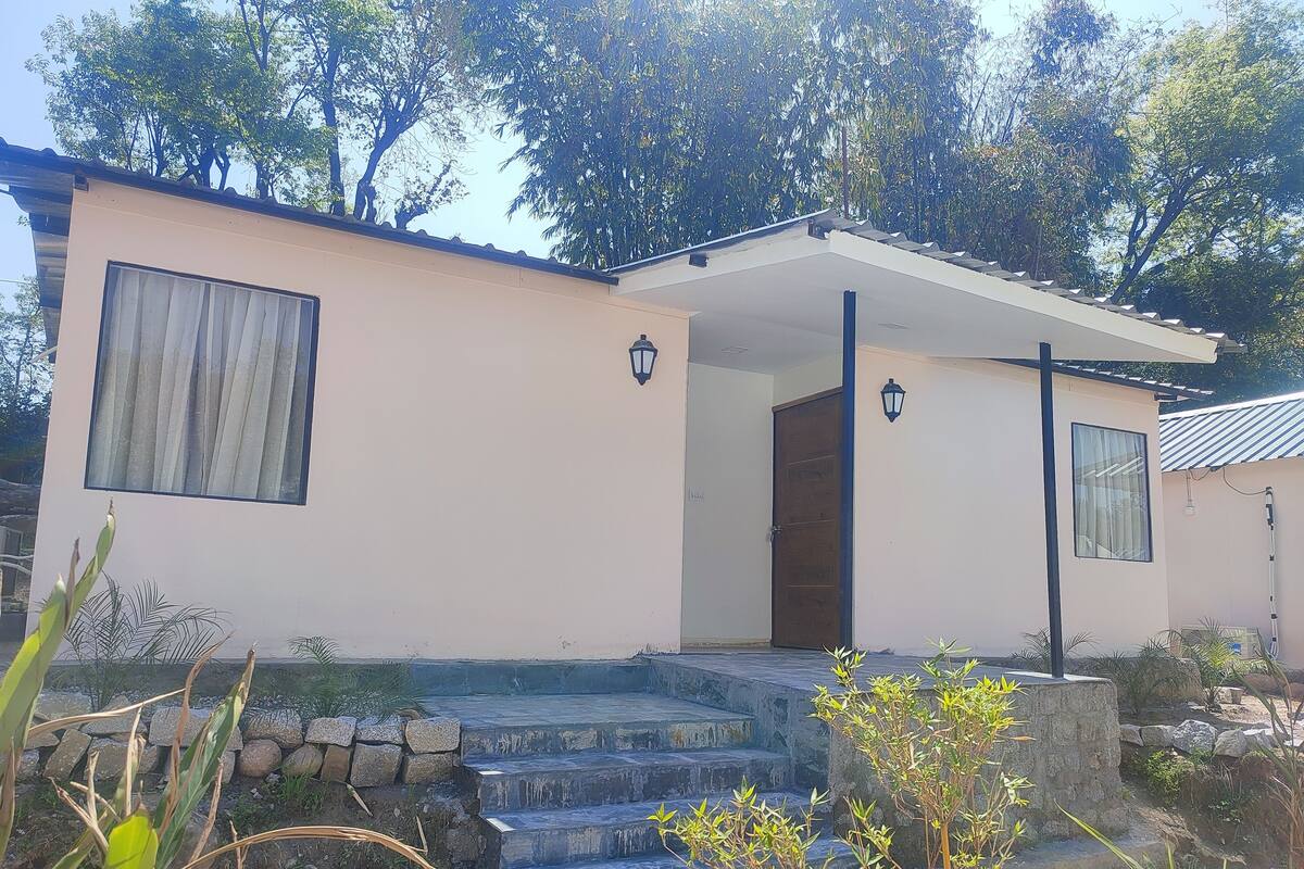 Un edificio de dos pisos con techo plano, una puerta principal y un pequeño porche con escalones.