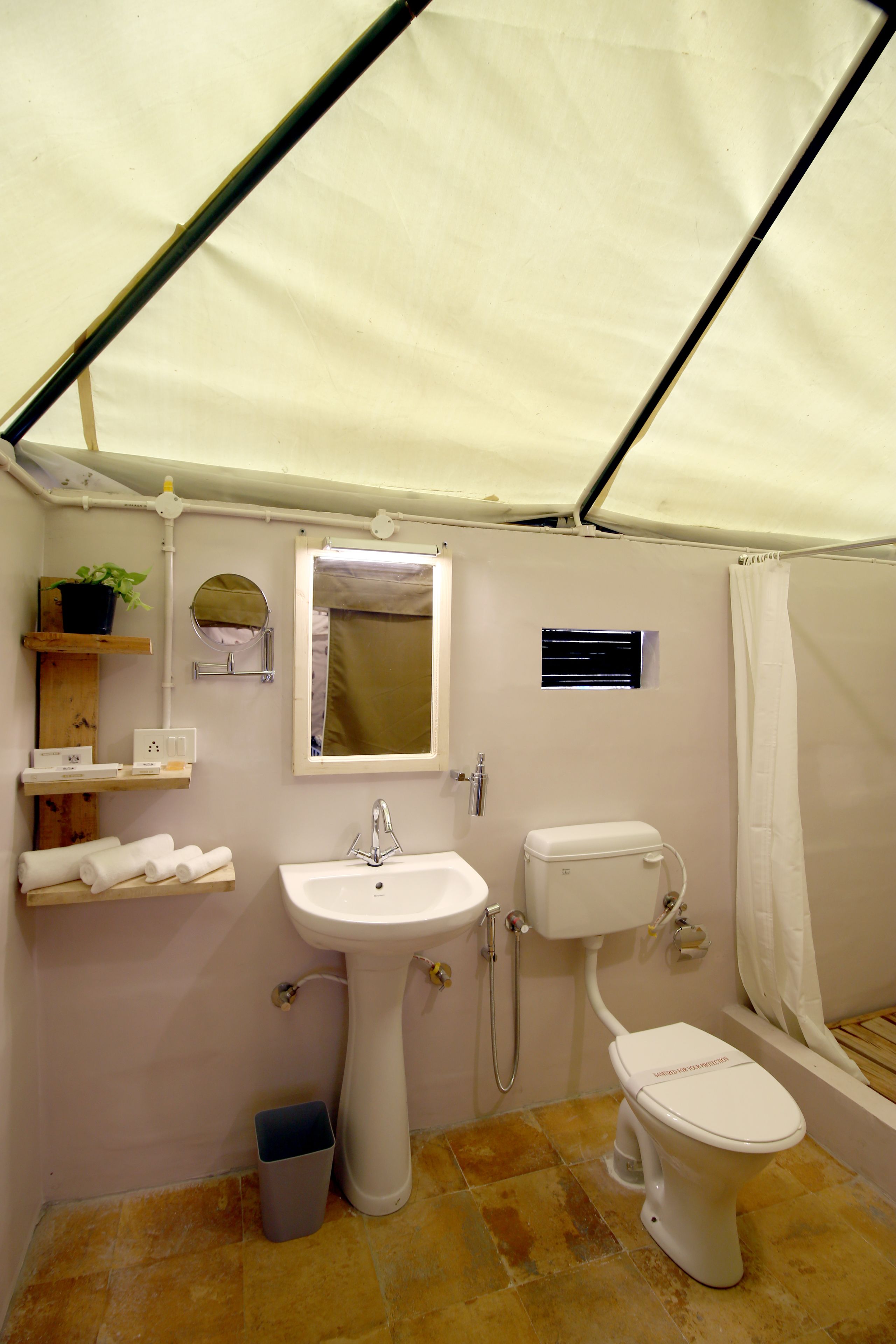 Une salle de bain compacte et bien éclairée, équipée d’un lavabo, de toilettes et d’un espace douche.