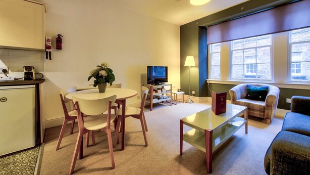 Um espaço compacto com cozinha compacta, área de jantar com mesa e cadeiras, sofá, televisão e uma janela grande com vista.