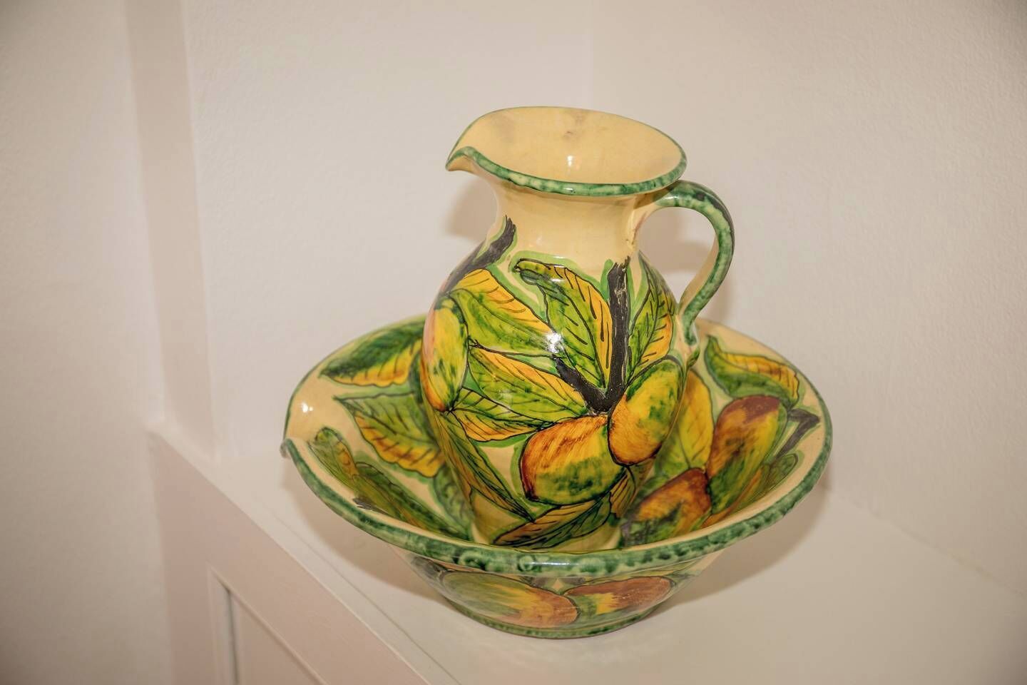 Un oggetto di ceramica con un motivo floreale, posato su una superficie bianca.