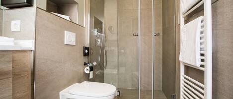Un baño moderno con inodoro, ducha con mampara de vidrio y un perchero para toallas.