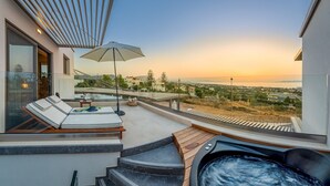 A modern outdoor terrace with a hot tub, lounge chairs, and a view of the landscape. - Onira Suite Dreams (Hersonissos)