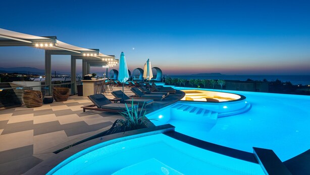 A rooftop infinity pool with lounge chairs and umbrellas, surrounded by a covered patio area with seating and a bar. - Onira Suite Dreams (Hersonissos)