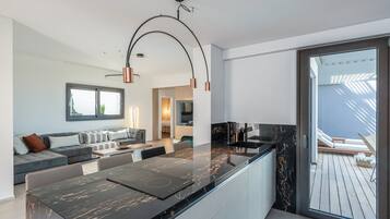 A modern kitchen with a black marble countertop, a built-in oven, and a large window overlooking a wooden deck.