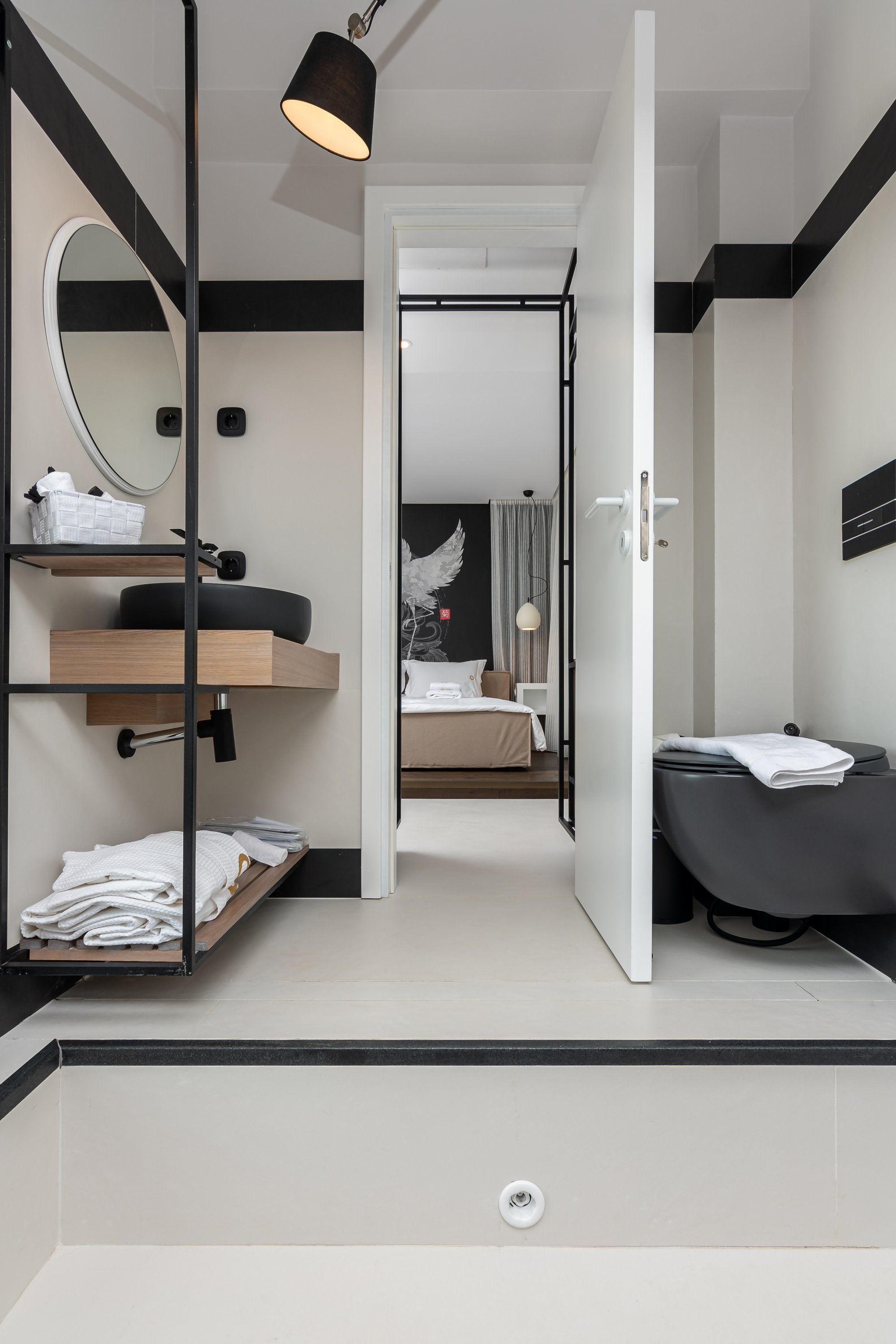 Un baño moderno con tocador de madera, un espejo y una bañera negra.