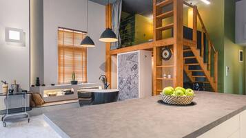A modern kitchen with a central island, wooden staircase, and pendant lighting.