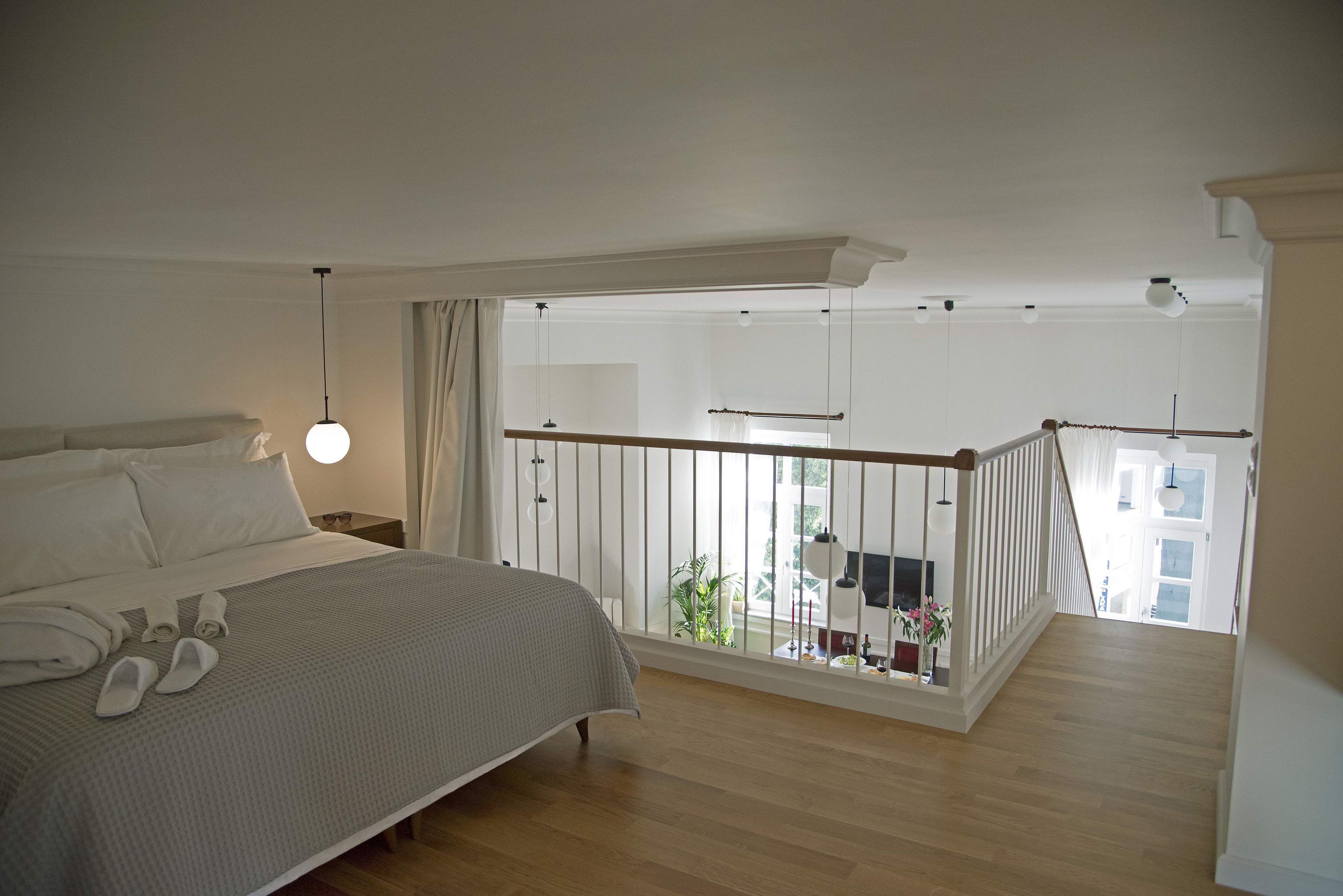 A bedroom with a large bed, a balcony with a railing, and a view of the outside.