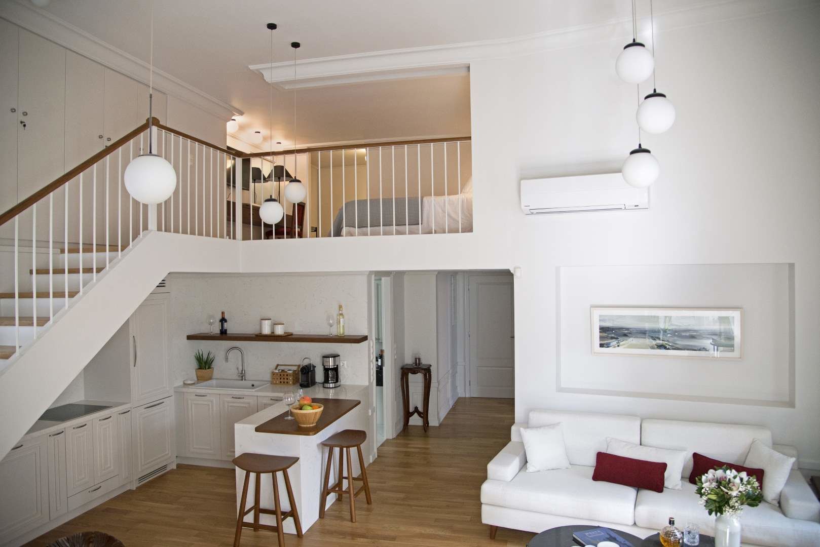 Amplio loft con cocina, comedor y sala de estar. Una escalera conduce a un nivel superior con cama.