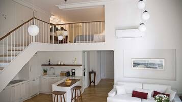 Amplio loft con cocina, comedor y sala de estar. Una escalera conduce a un nivel superior con cama.