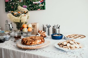 A table with a variety of food items including a loaf of bread, pastries, and a pie. - Agriturismo Cà del Nono (Moasca)