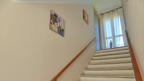 A staircase with wooden handrails and beige steps leading to a room with a window. - Agriturismo Cà del Nono (Moasca)
