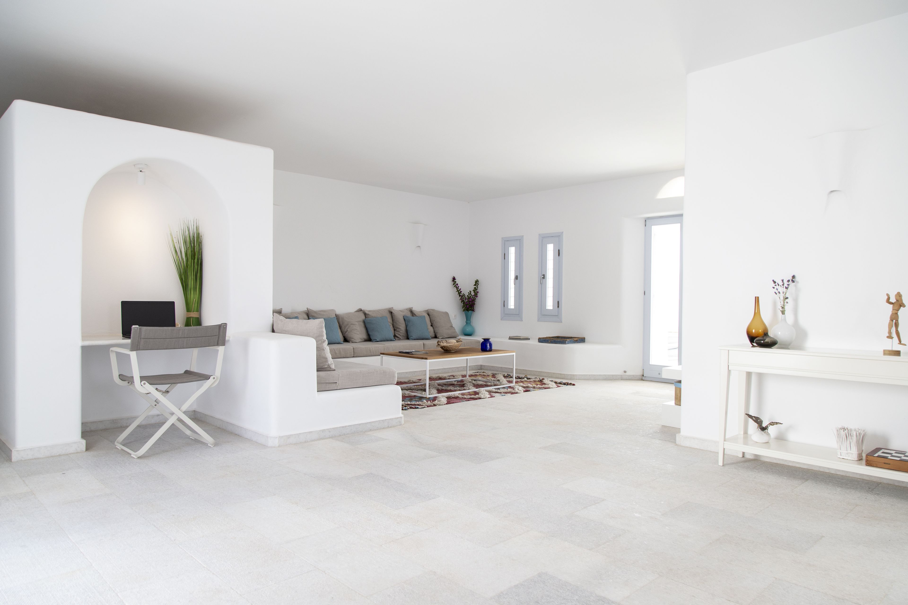 A modern living room with a white sofa, a small coffee table, and a white console table with decorative items.