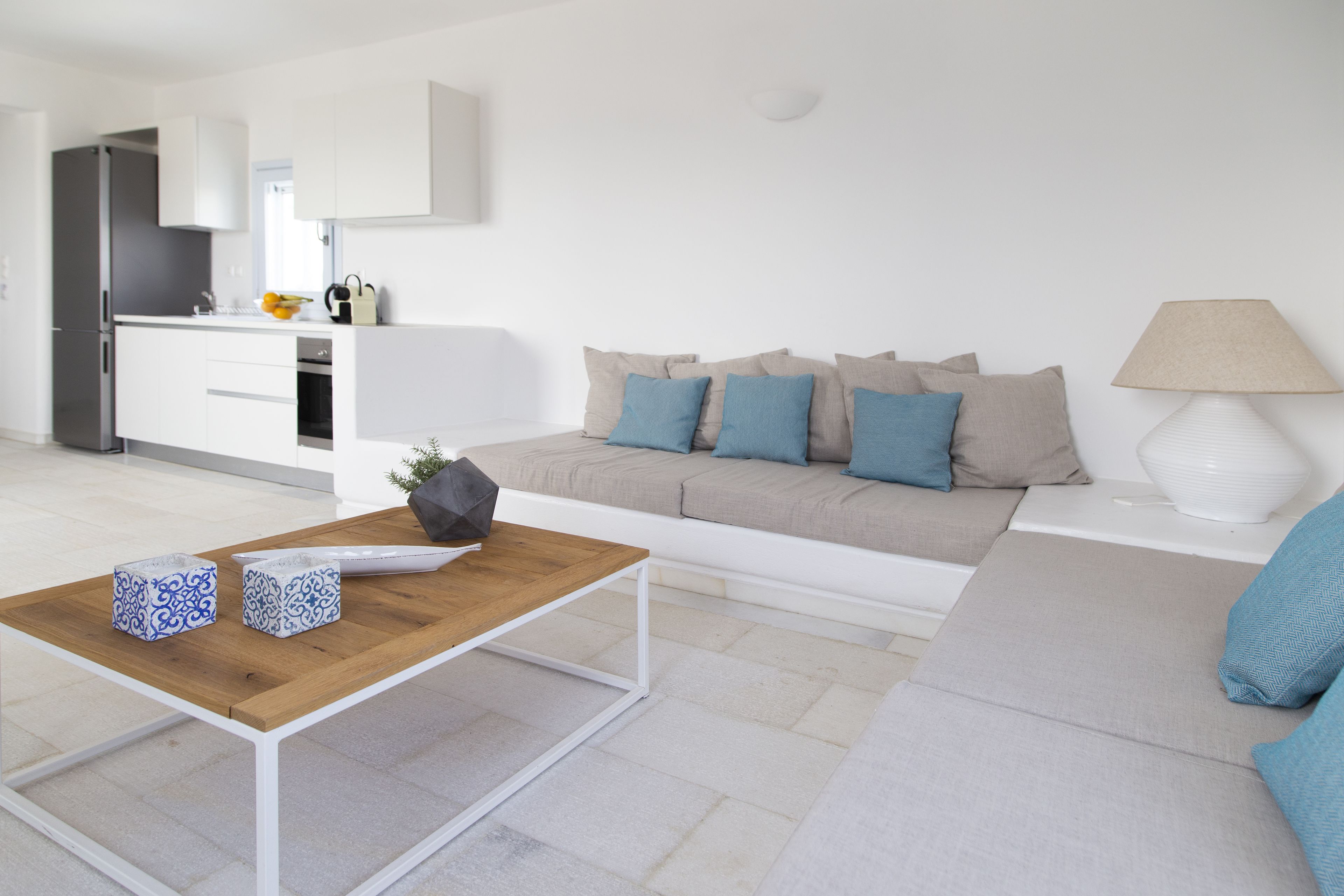 A modern living room with a wooden coffee table, a sofa, and a kitchen in the background.