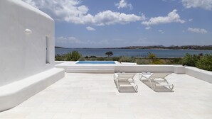 A rooftop terrace with a pool, white walls, and a view of the sea. - The Sand Collection (Paros)