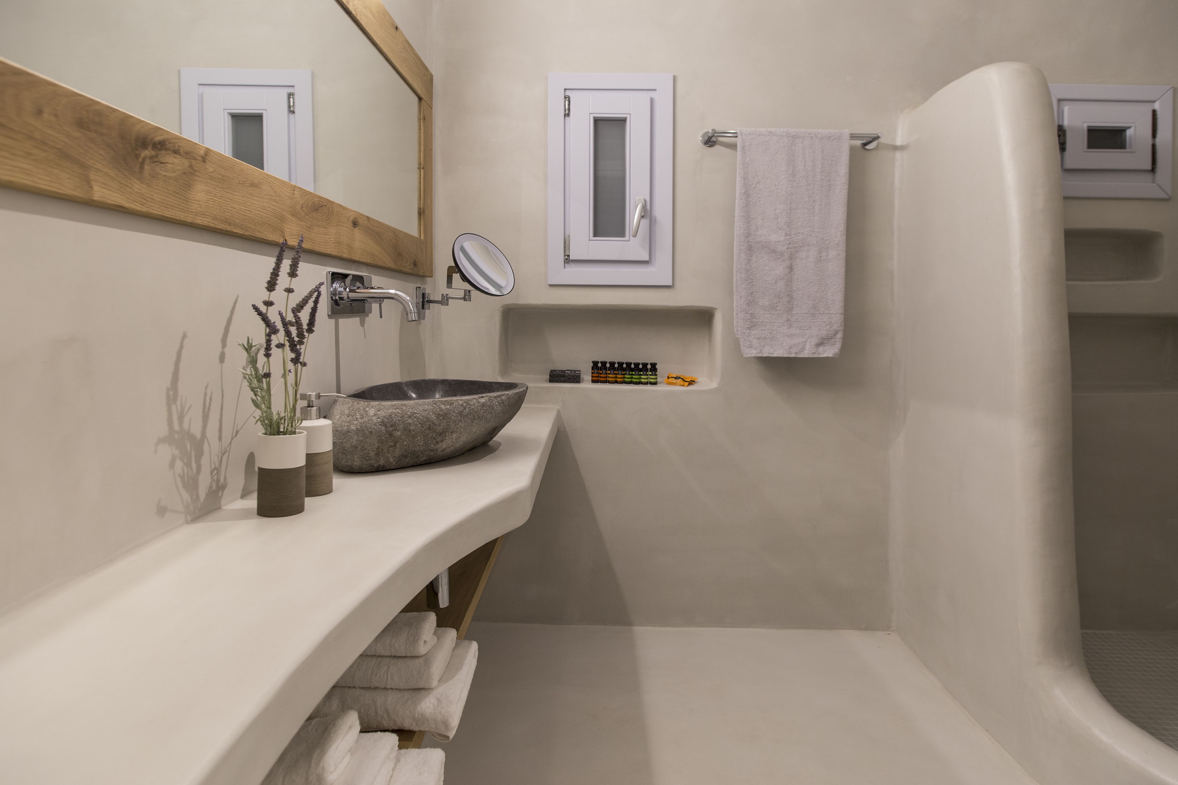 Ein modernes Badezimmer mit einer großen Badewanne, einem Waschbecken mit Steinbecken, einem Spiegel und einem Handtuchhalter.