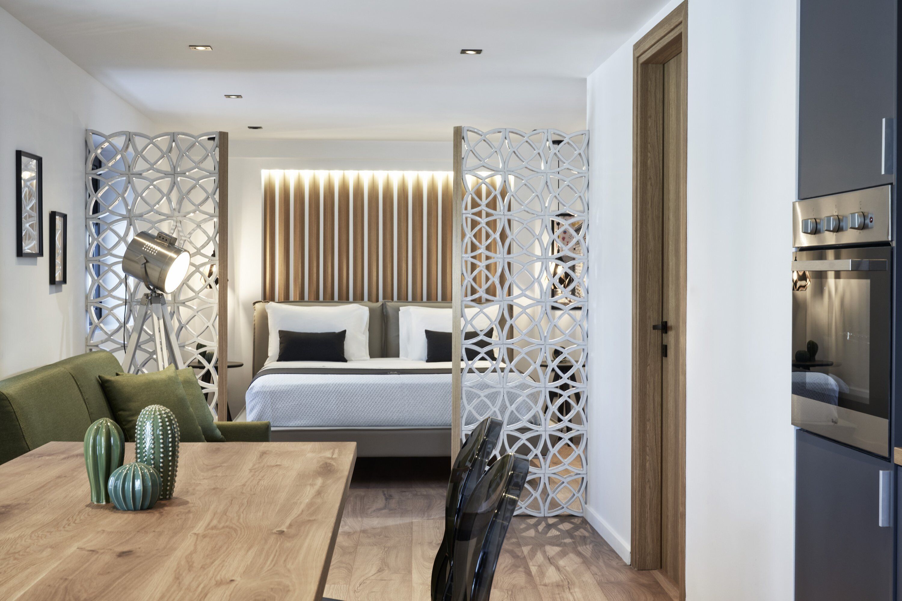 A modern bedroom with a bed, a wooden dining table, and a green sofa.