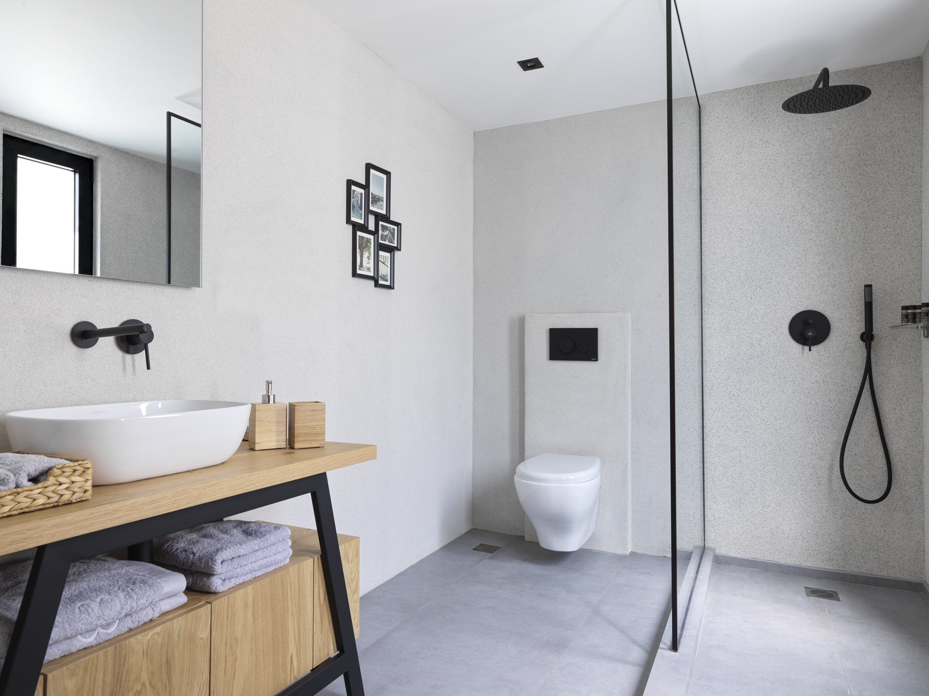 Un baño moderno con una bañera independiente, un inodoro y una ducha a ras de suelo.