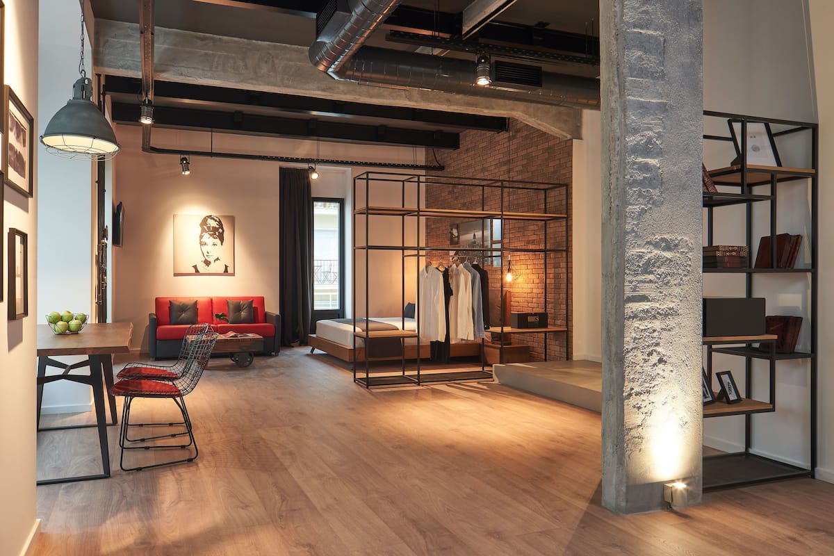 Ein modernes Interieur mit Holzboden, einem roten Sofa, einem Essbereich mit Tisch und Stühlen sowie einem Kleiderständer.