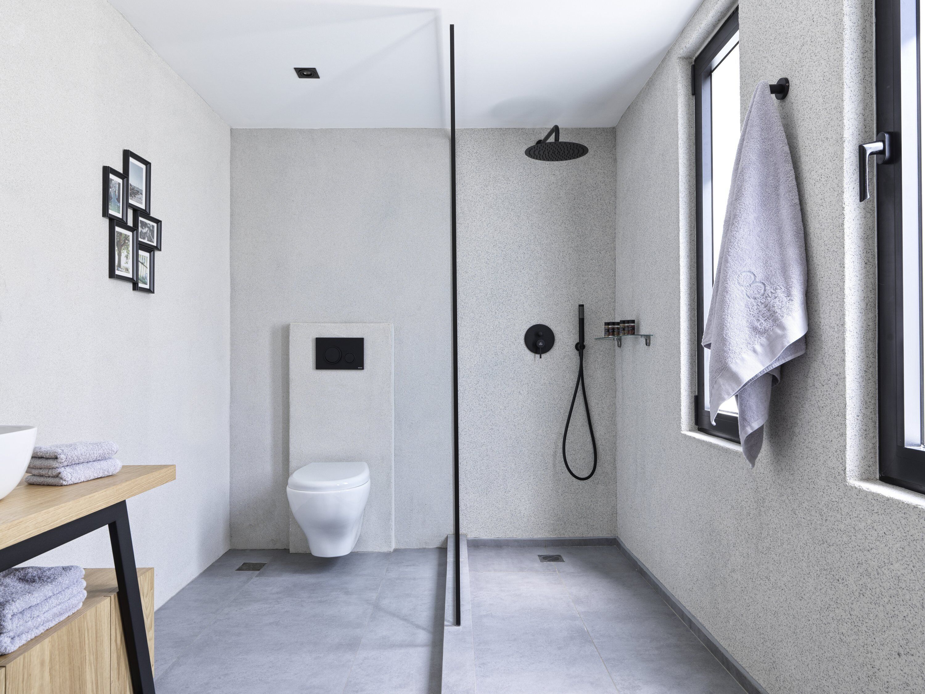 Une salle de bain moderne dotée d’une douche à parois de verre, de toilettes et d’un lavabo avec un plan de travail en bois.