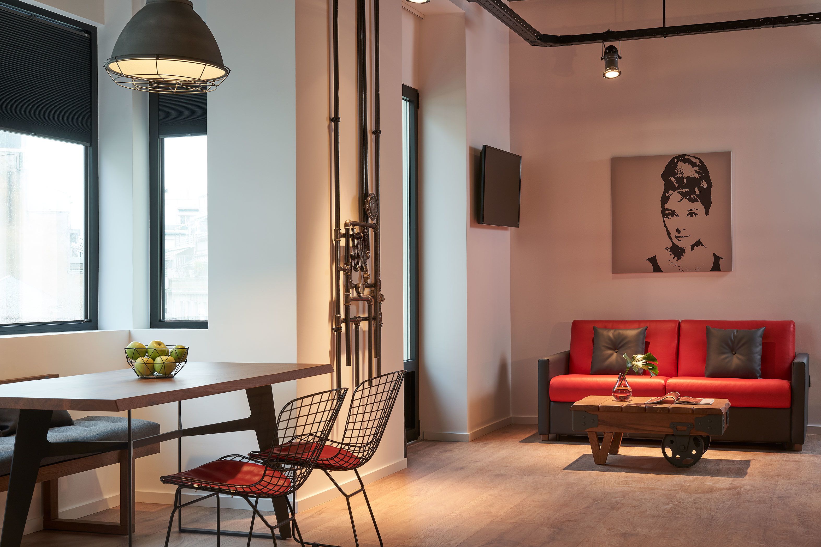 A modern living room with a red sofa, a wooden coffee table, and a dining area with a table and chairs.