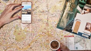Een gedetailleerde kaart met notities, een smartphone die een webpagina toont, een reisgids en een koffiekop.