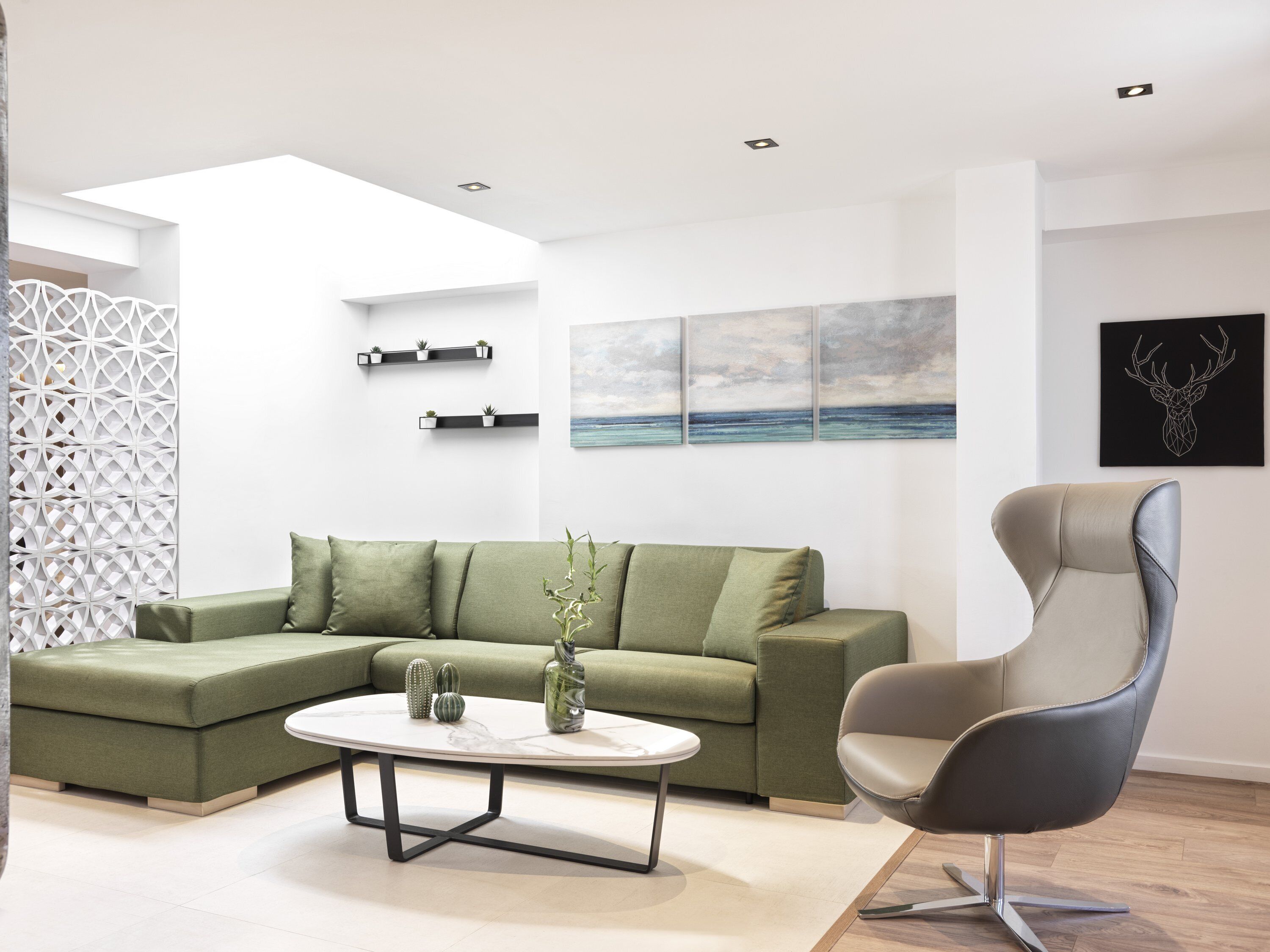 Un salon moderne avec un canapé d’angle, une table basse ronde et un fauteuil contemporain.