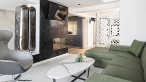 A modern living room with a sofa, a chair, a coffee table, and a TV mounted on a black wall.