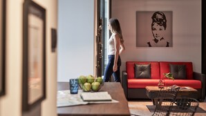 A modern living room with a red sofa, a coffee table with a bowl of fruit, and a framed picture on the wall.