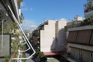 A narrow urban street with multi-story buildings, some with balconies and satellite dishes.