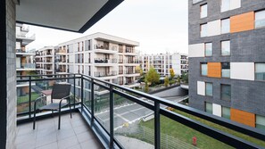 A modern apartment building with multiple balconies, a view of the surrounding area, and a clear sky.