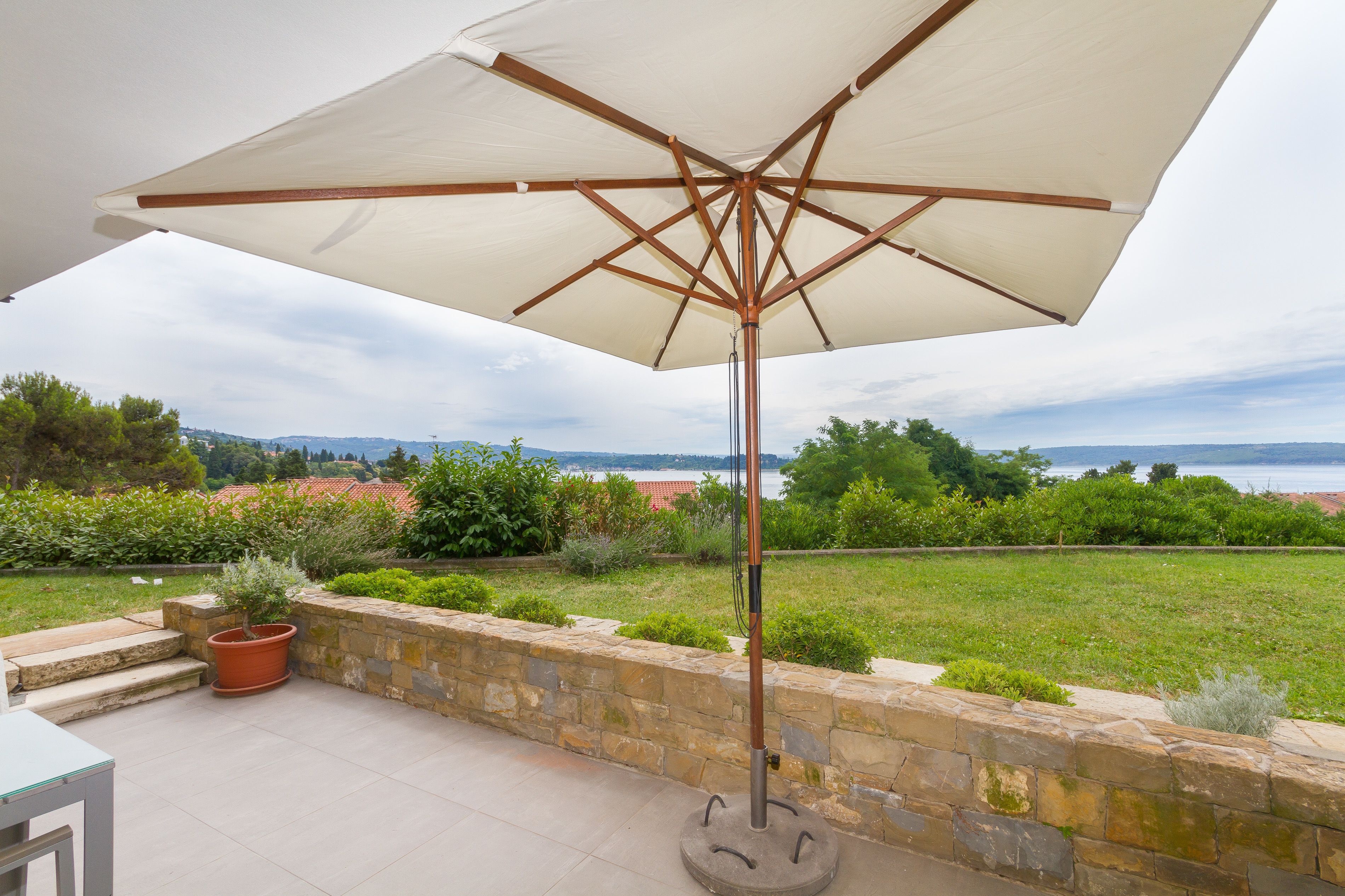 An outdoor patio area with a large umbrella, stone steps, and a view of the sea.