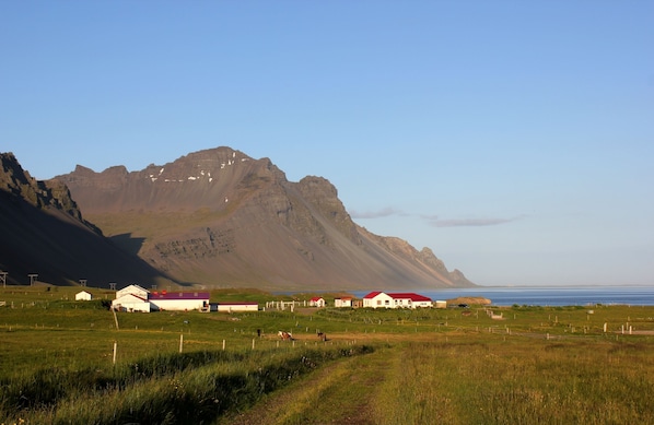 A rural landscape with houses, a mountain, and a body of water.