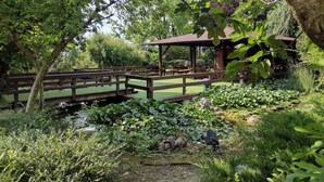 A wooden bridge over a pond, surrounded by lush greenery and a gazebo. - Parc Hotel Casa Mia (Lazise)