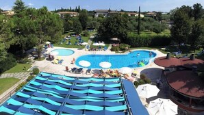 A hotel with a large outdoor swimming pool, lounge chairs, and umbrellas. - Parc Hotel Casa Mia (Lazise)