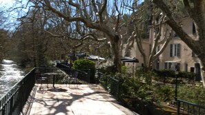 A riverside walkway with a wooden deck, metal railing, and benches.