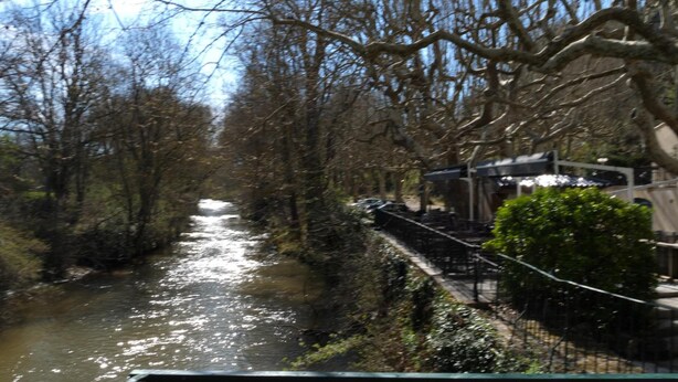 A river running through a park with trees and a bridge. - Maison Arquier (Aix-en-Provence)