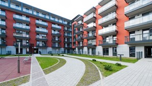 A modern apartment complex with multiple balconies, a central courtyard, and a pedestrian pathway. - Apartamenty Sun & Snow Rakowicka Podkowa (Kraków)