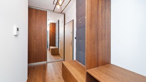 A modern hallway with wooden flooring and a bench. - Apartamenty Sun & Snow Rakowicka Podkowa (Kraków)