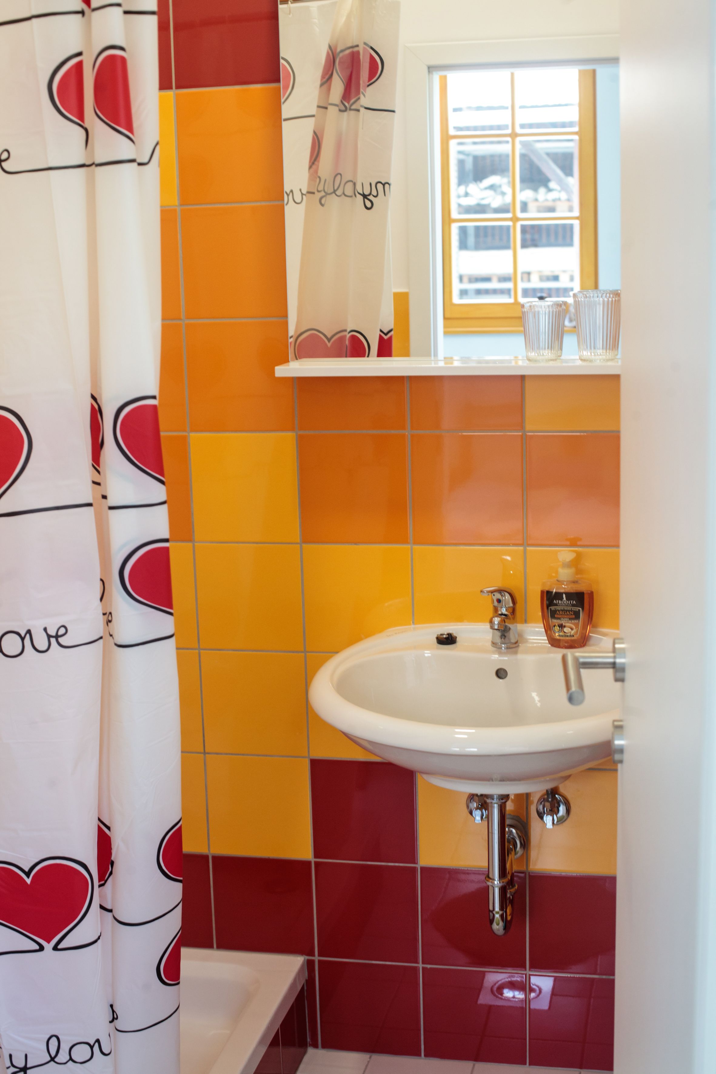 A bathroom with a sink, a mirror, and a window.