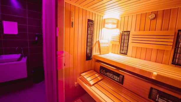 A sauna with wooden benches and a wall-mounted heater. - BikeSki B&B (Mežica)