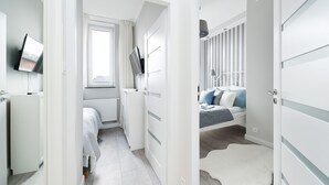 A modern bedroom with a bed, a TV, a radiator, and a window.