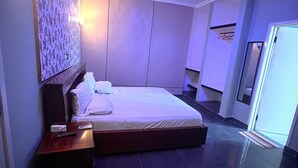Een moderne hotelkamer met een groot bed, een nachtkastje, een wandairconditioner en een plafondlamp.