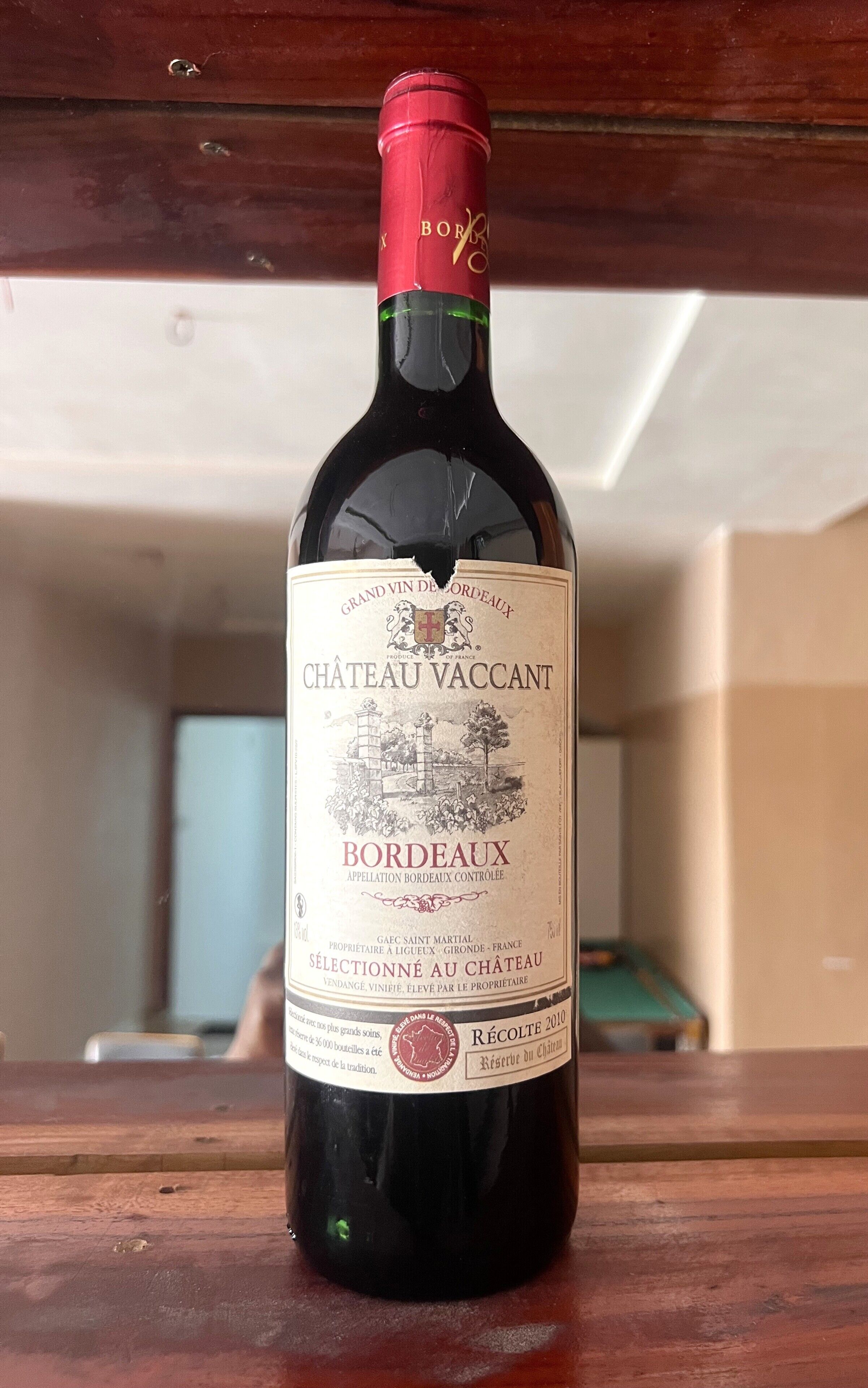 A bottle of Château Vaccant wine on a wooden surface.