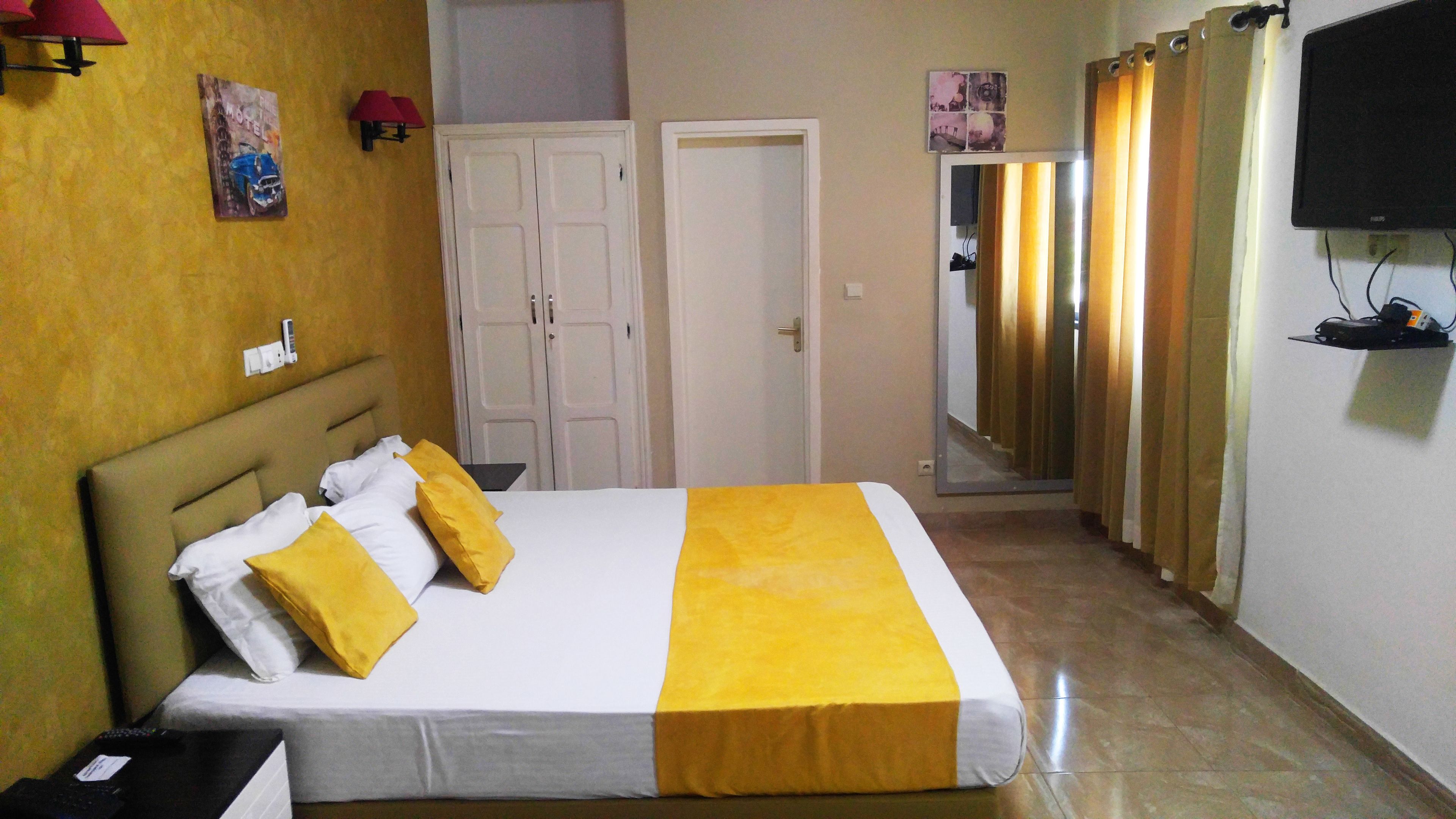 A hotel room with a bed, a wardrobe, a television, and a mirror.