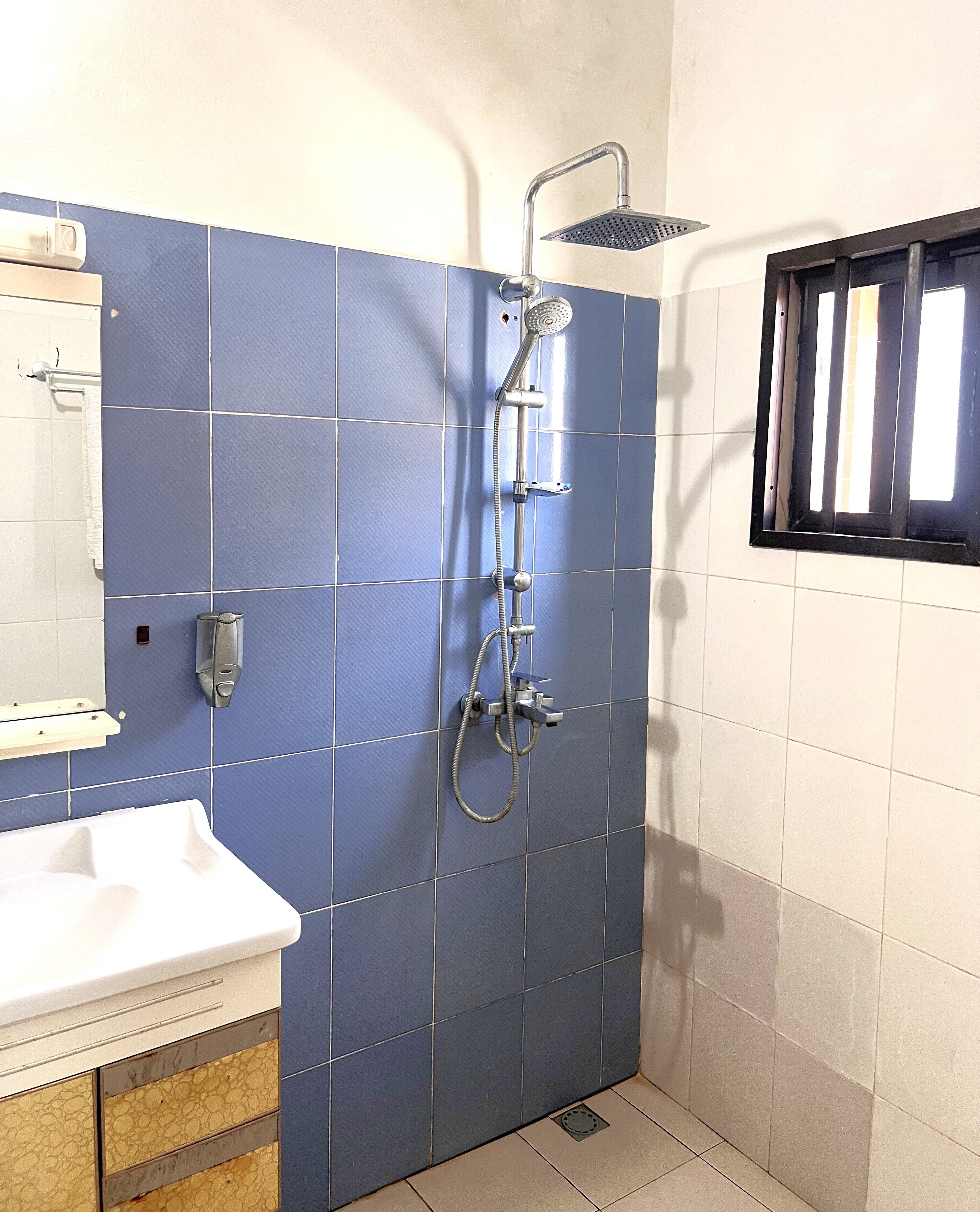 Ein Badezimmer mit Dusche, Waschbecken und Fenster.