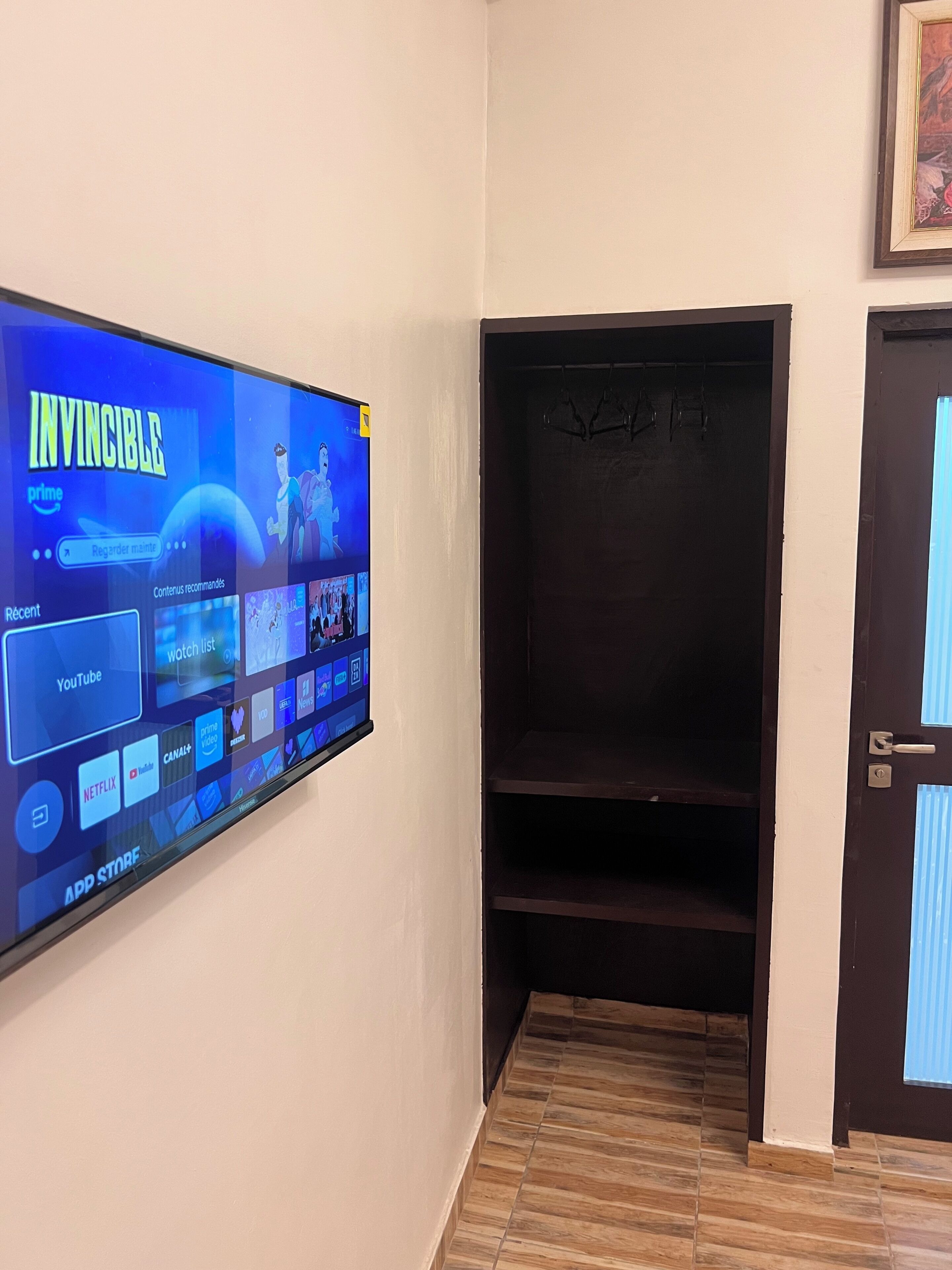 Un téléviseur à écran plat fixé au mur affiche l’interface d’un service de diffusion en continu, avec différentes icônes d’applications.
